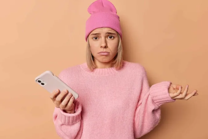 Telefonuna bakan üzgün kız, muhtemelen sosyal medyada engellenmesine tepki gösteriyor.